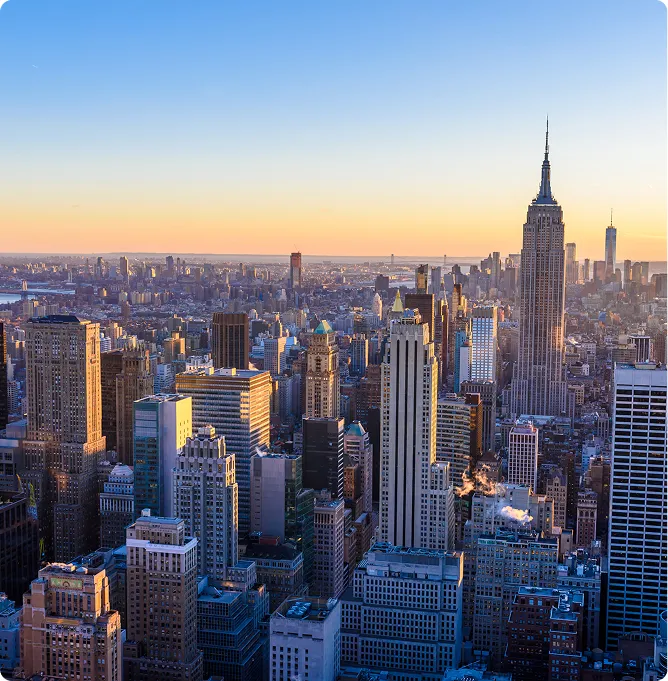 Aerial view of New York City skyline at sunset with Empire State Building prominent.