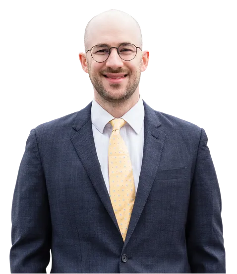 Portrait of a bald man wearing glasses, a dark suit, white shirt, and yellow tie.