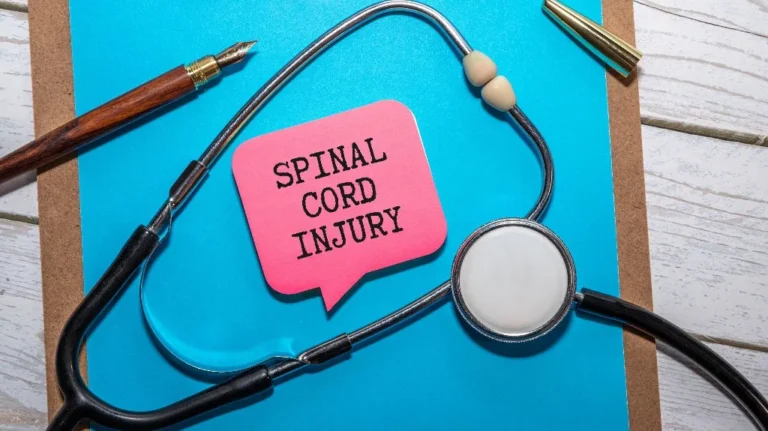 Stethoscope, fountain pen, and pink speech bubble with "SPINAL CORD INJURY" text on blue clipboard.