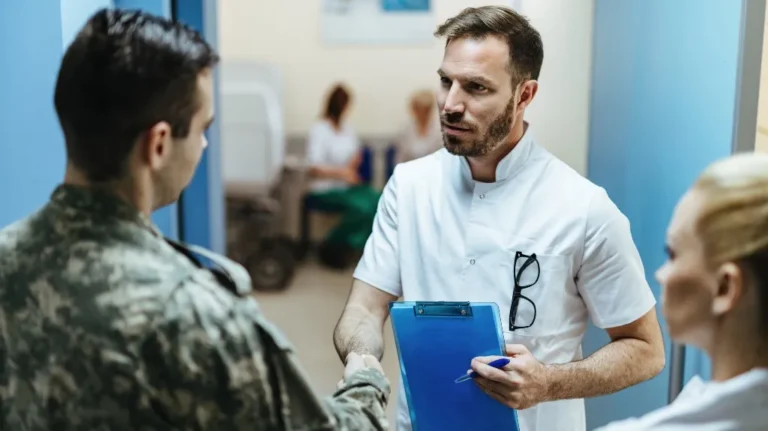 Medical professional in white coat shaking hands with soldier in camouflage uniform, holding blue clipboard.